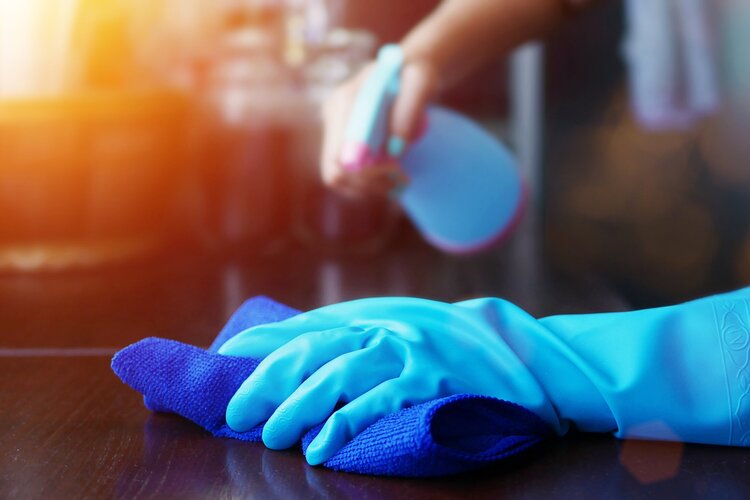 Person cleaning desktop with rubber gloves on
